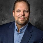 man in a suit and blue shirt in a cloud supply chain setting