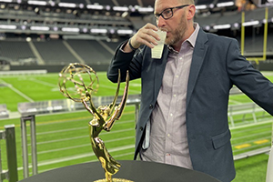 A Man Celebrating With A Cup Of Coffee Next To A Trophy At NAB 2024